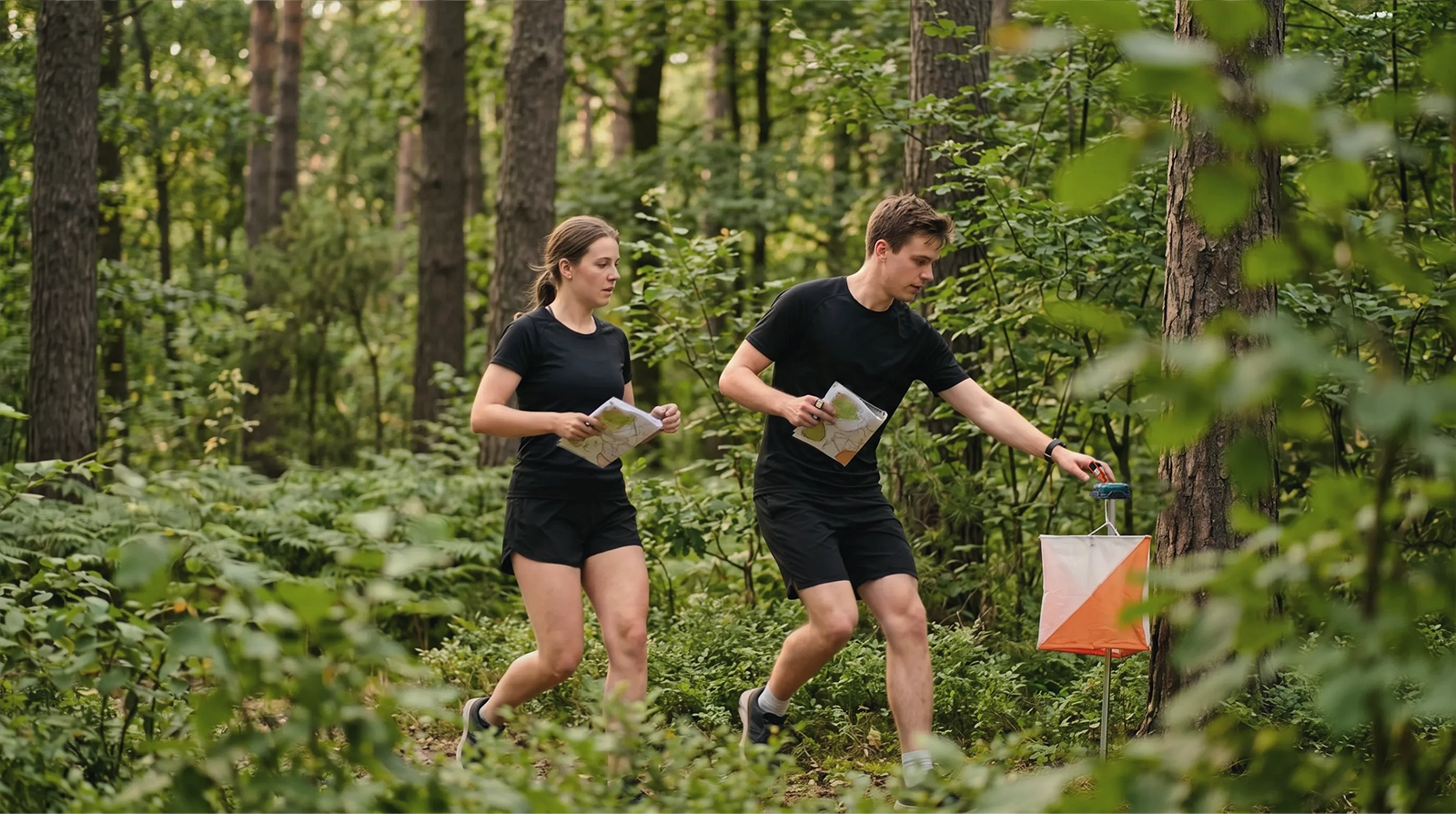 Two runners run toward a control in the forest